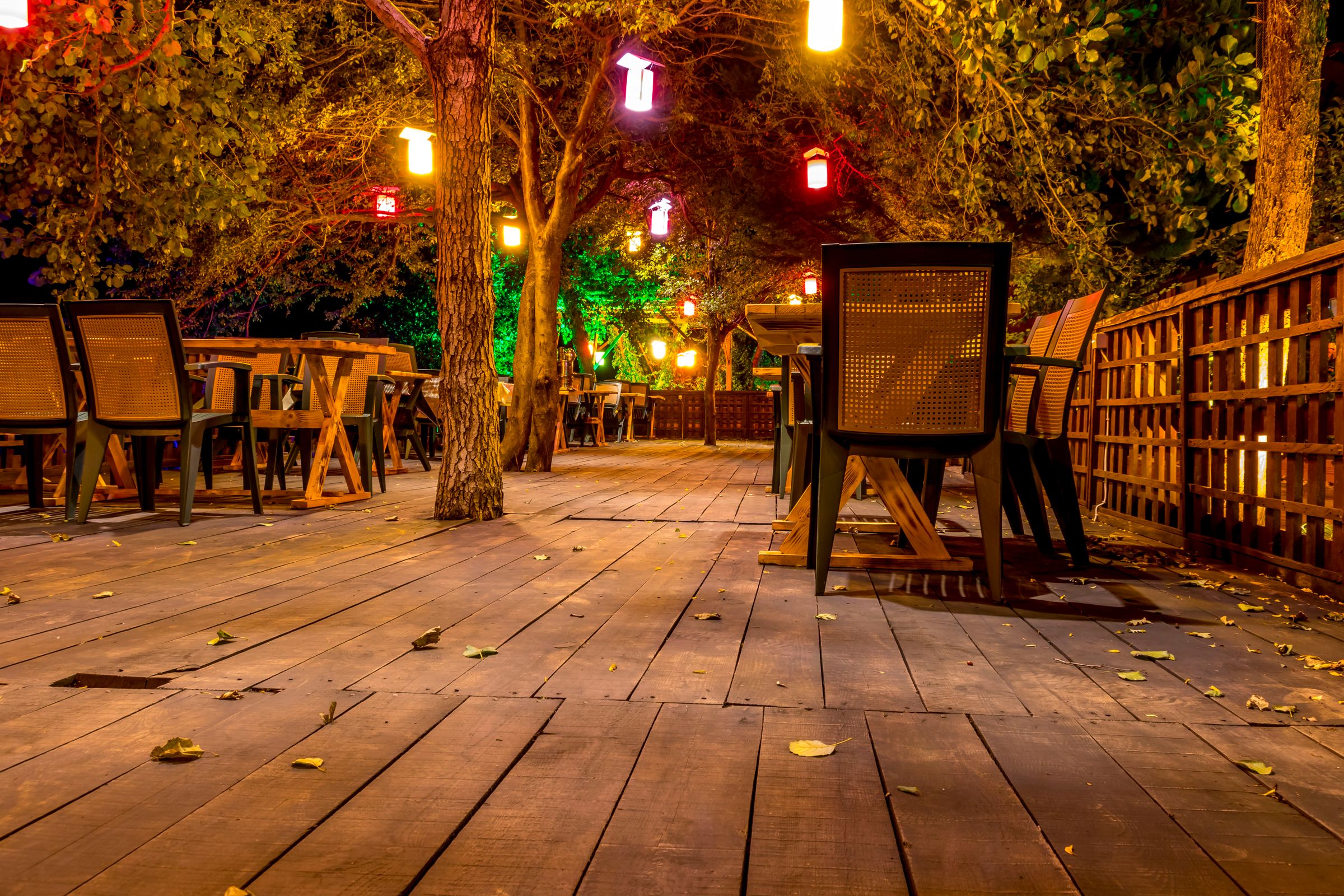 An outdoor table on a timber deck under hanging lights