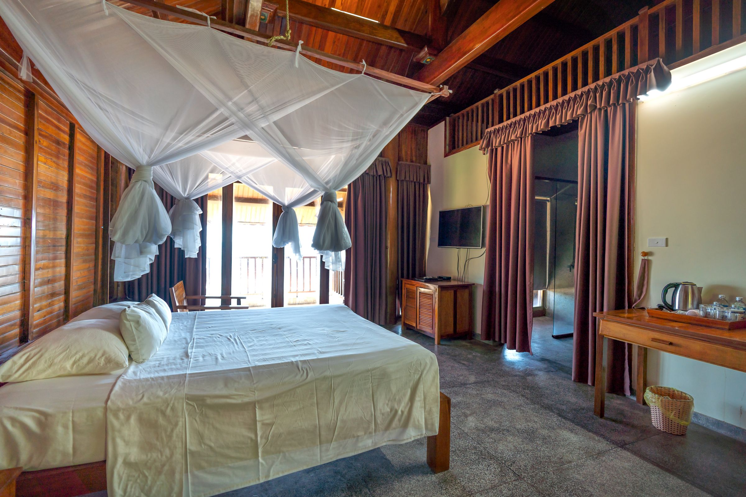 A canopy bed in a tropical suite open to the greenery